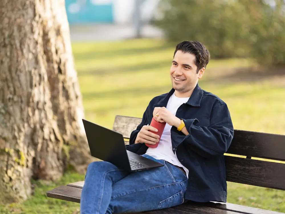 ヘンケル社員が公園のベンチに腰掛けてノートパソコンで作業する様子。