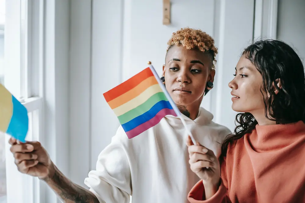 LGBTQ+の旗を持って会話する2人の女性