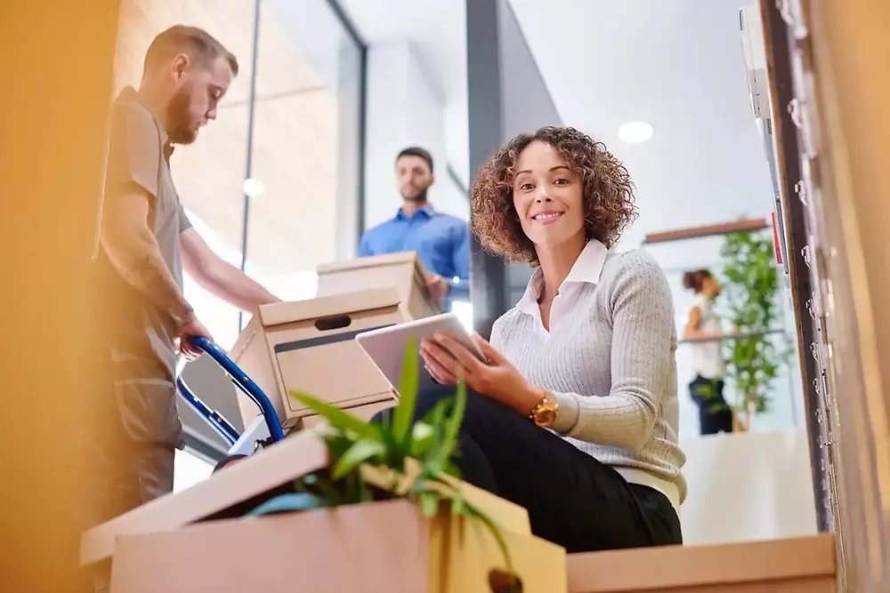 配達員が自宅で笑顔の女性に荷物を手渡している。